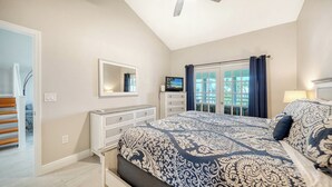 A bedroom with a large bed, a dresser, a television, and a view of the outdoors through a glass door. - Heated Pool, FREE WIFI Luxury Bayside Condo Across from Siesta Key Beach |  Beautiful 3BR/2BA Gulf & Bay Club Bayside Condo (Sarasota)
