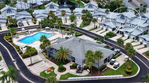 Un quartier résidentiel comprenant plusieurs maisons, une piscine et une entrée sécurisée par un portail.