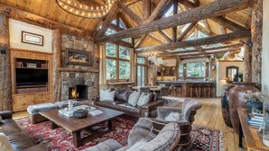 A rustic interior with a stone fireplace, leather furniture, and a wooden ceiling.