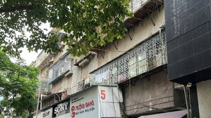 A street with parked motorcycles, a building with multiple signs including 'SONY' and 'Canon,' and a tree providing shade. - Fully Equipped 2BR/2BA Apt Old Quarter & Hoan Kiem (Hà Nội)