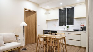 A modern kitchen with a dining table, chairs, a sofa, and a floor lamp. - Fully Equipped 2BR/2BA Apt Old Quarter & Hoan Kiem (Hà Nội)