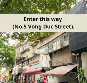 A street view with a sign indicating 'Enter this way (No.5 Vong Duc Street)'.