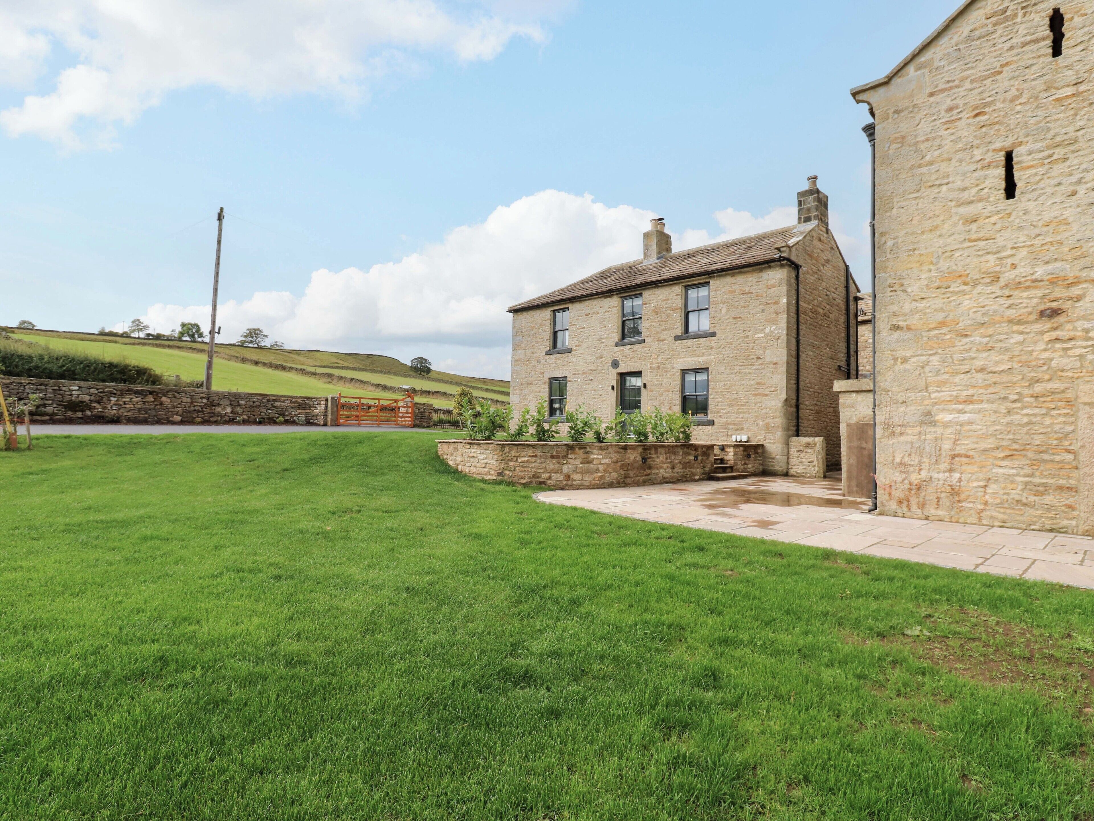 A stone building with a grassy yard and a stone wall.