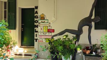 Een kamer met een groene deur, een stapel koffers en een standbeeld van een persoon.