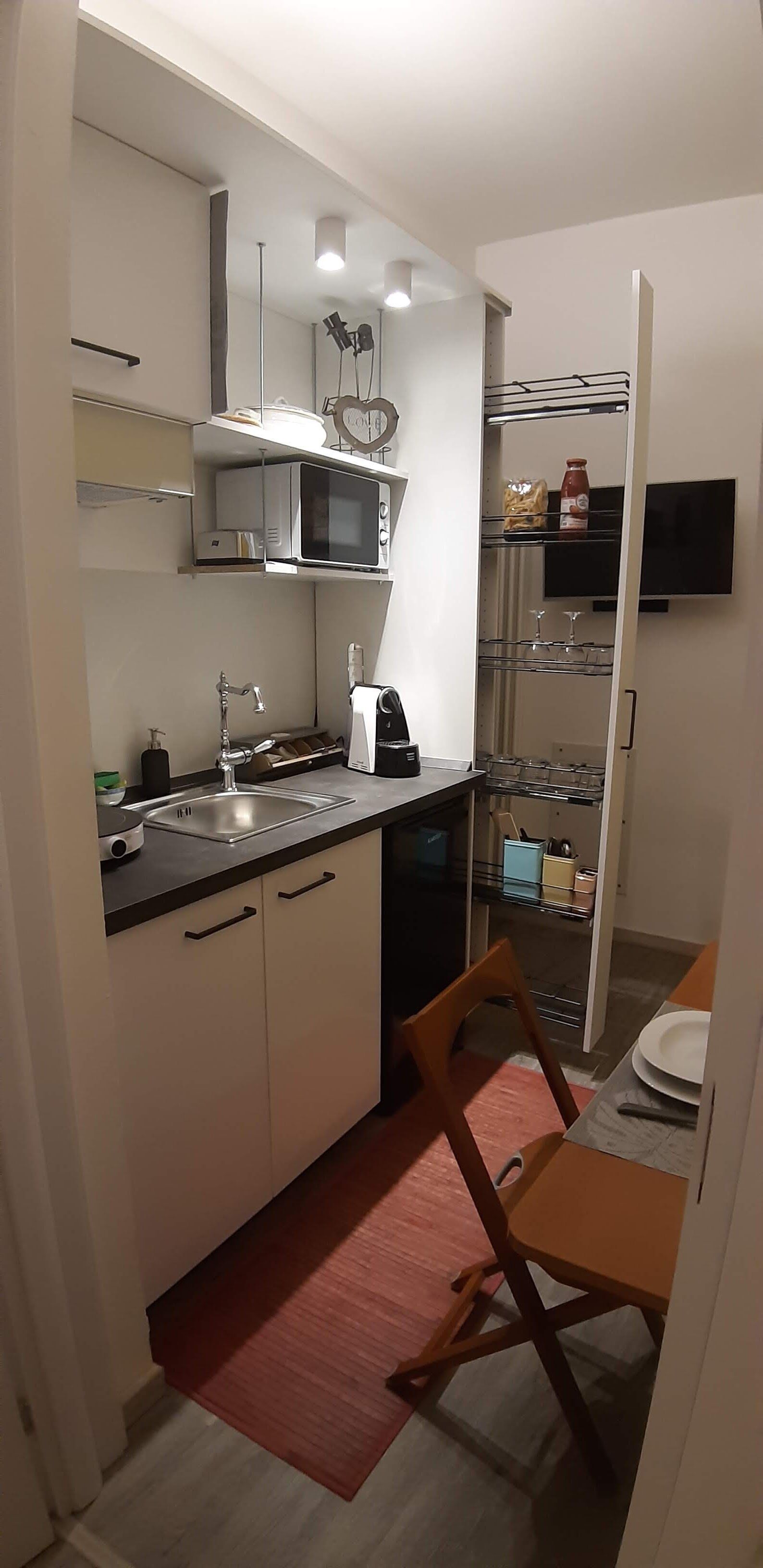 A compact kitchen with a microwave, sink, and a small dining area with a chair and table.