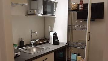 A compact kitchen with a microwave, sink, and a small dining area with a chair and table.