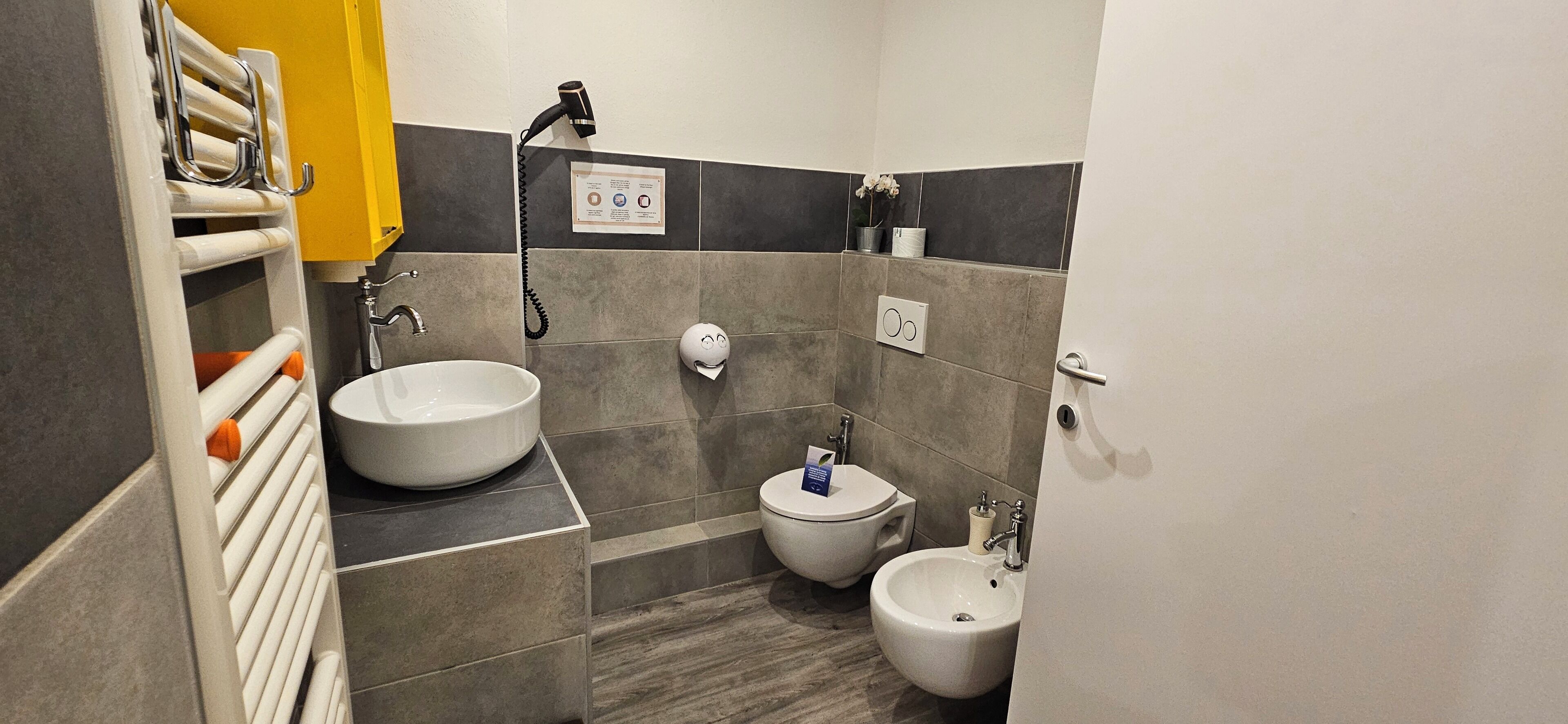A modern bathroom with a large sink, two bidets, a hairdryer, and a towel rack.