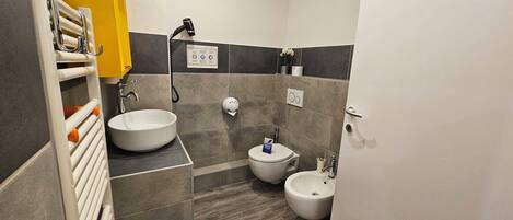 A modern bathroom with a large sink, two bidets, a hairdryer, and a towel rack.