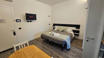 Ein Hotelzimmer mit Bett, Fernseher, Schreibtisch und Stuhl.