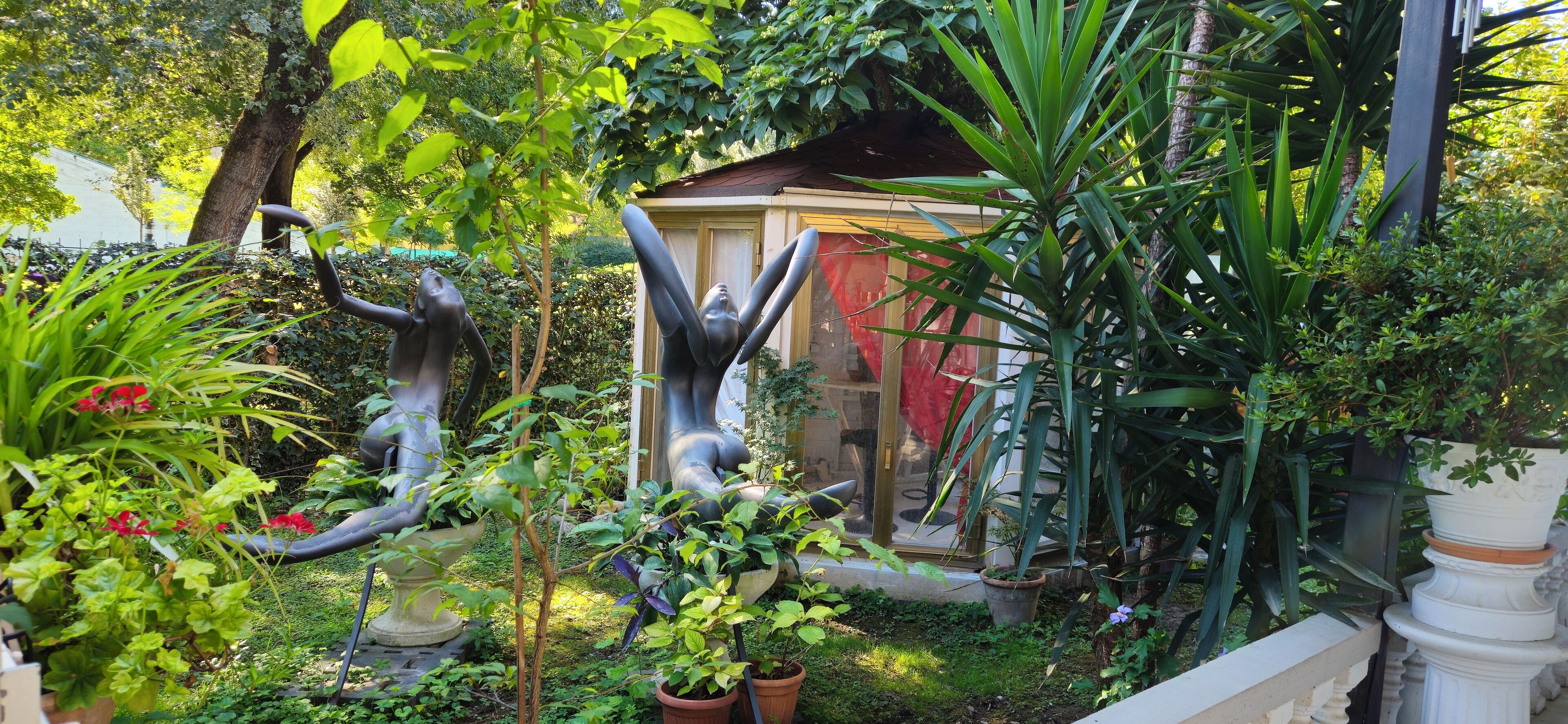 Un jardín con esculturas y plantas en macetas.