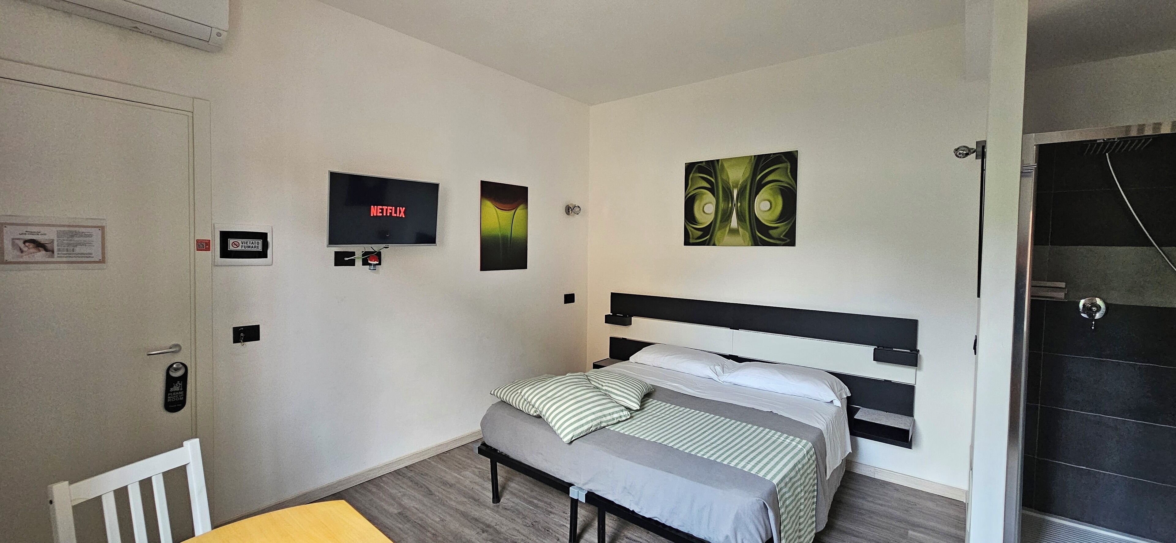Une chambre à coucher avec un lit, une télévision et des œuvres d’art accrochées au mur.