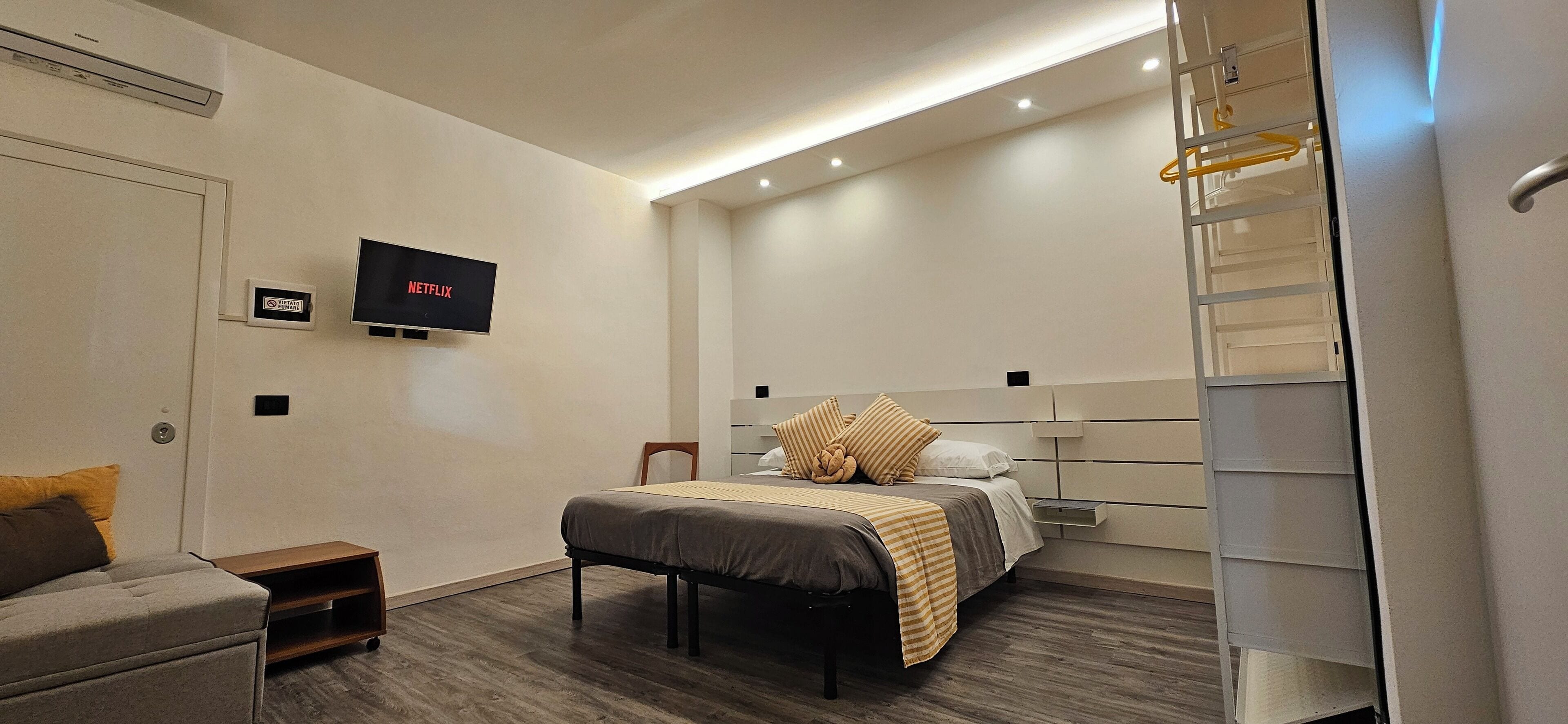 Camera d'albergo moderna con un letto, una TV a muro, un tavolino e un armadio a scomparsa.