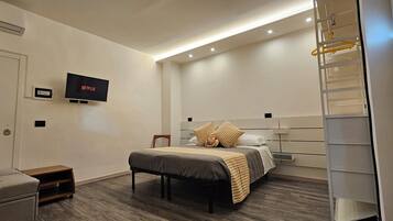 Camera d'albergo moderna con un letto, una TV a muro, un tavolino e un armadio a scomparsa.