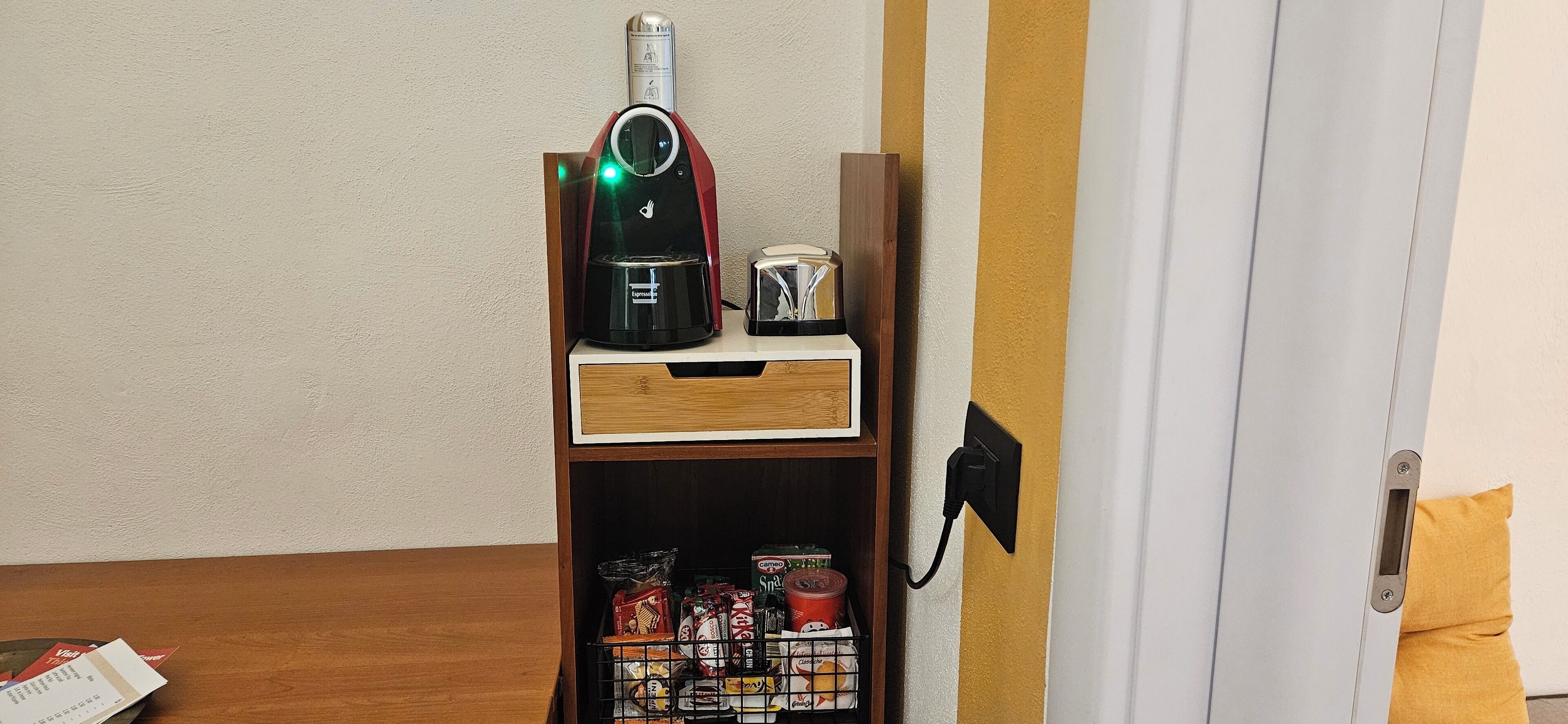 Une petite cuisine équipée d’une machine à café, d’un grille-pain et d’un étagère à épices.