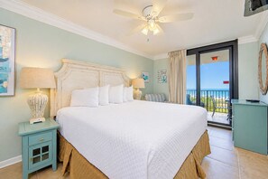 Une chambre d’hôtel avec un grand lit, un ventilateur de plafond, une vue sur la plage et un balcon.
