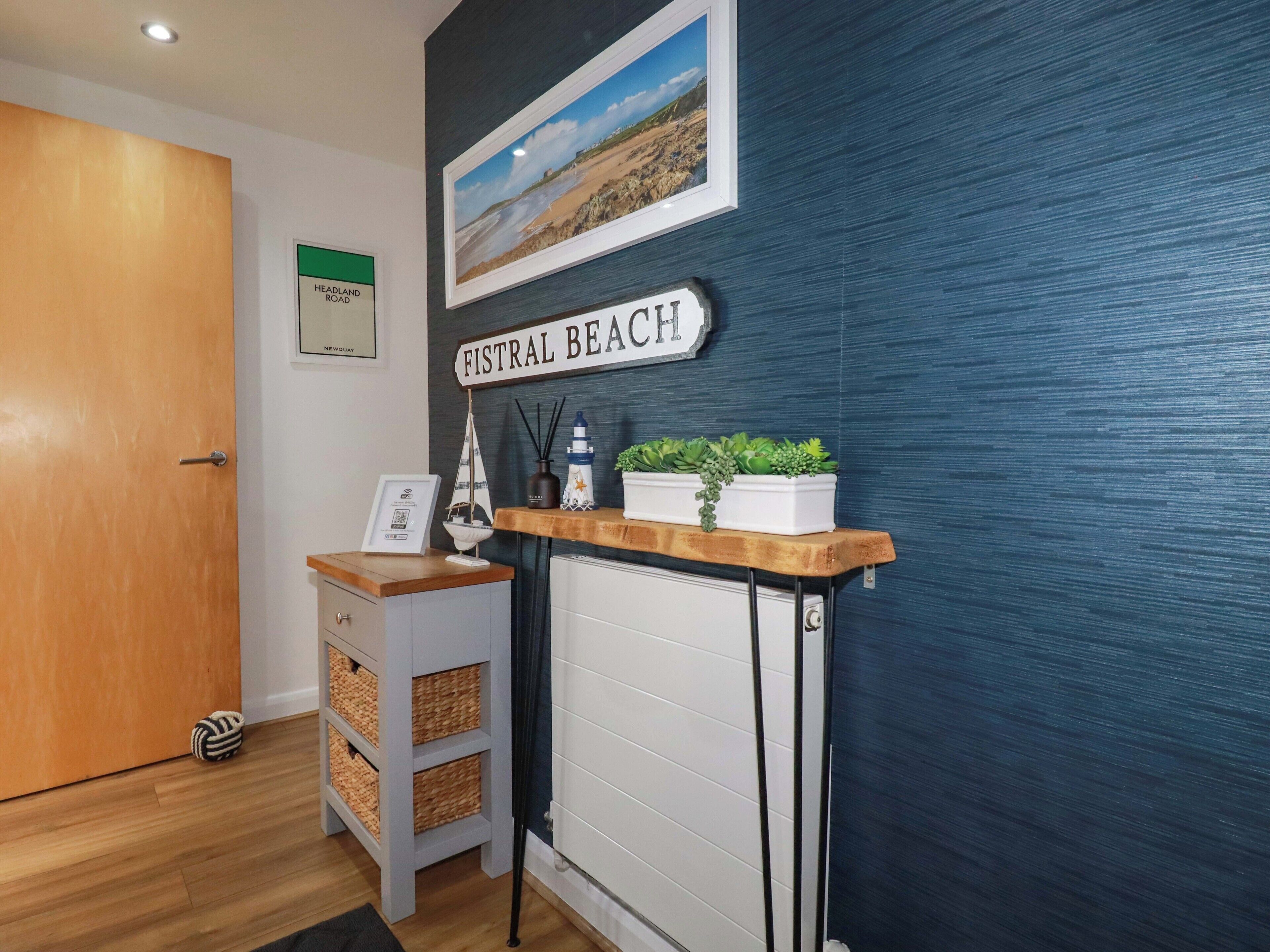 Ein Empfangsbereich mit einer Holztresen, einem gerahmten Bild von einem Strand und einem Schild mit der Aufschrift 'FISTRAL BEACH'.