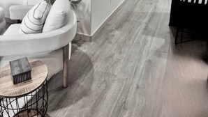 Een moderne keuken met een ingebouwde koelkast, een eethoek met een geruit tafelkleed, en een zithoek met een witte bank en een potplant.