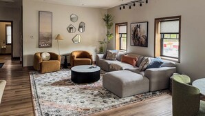 Un salon moderne avec un canapé d’angle, une table basse ronde et un tapis à motifs.
