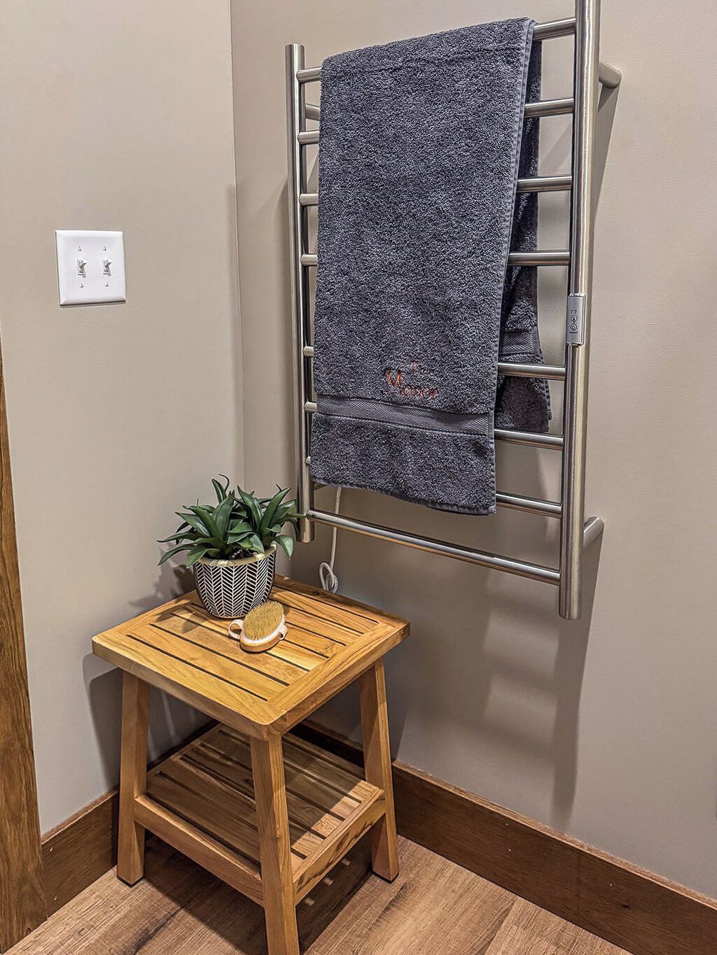 Ein Badezimmer mit Holzschemel, Blumentopf, Handtuchhalter und Steckdose.