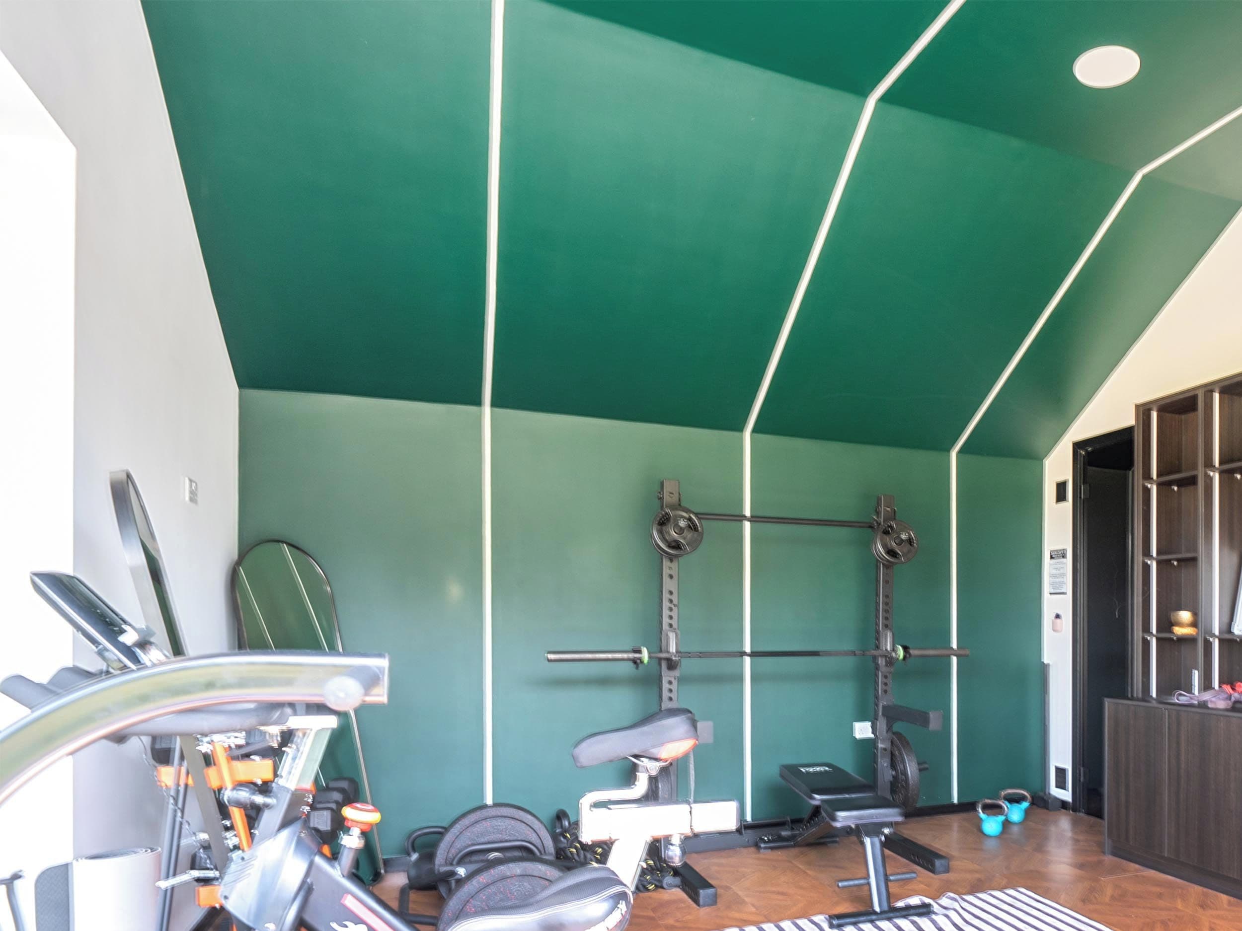 Un gimnasio con equipo de ejercicio, una banca de pesas y una estructura para sentadillas.