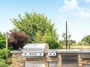 An outdoor grill with a stone base, a built-in sink, and a chimney.