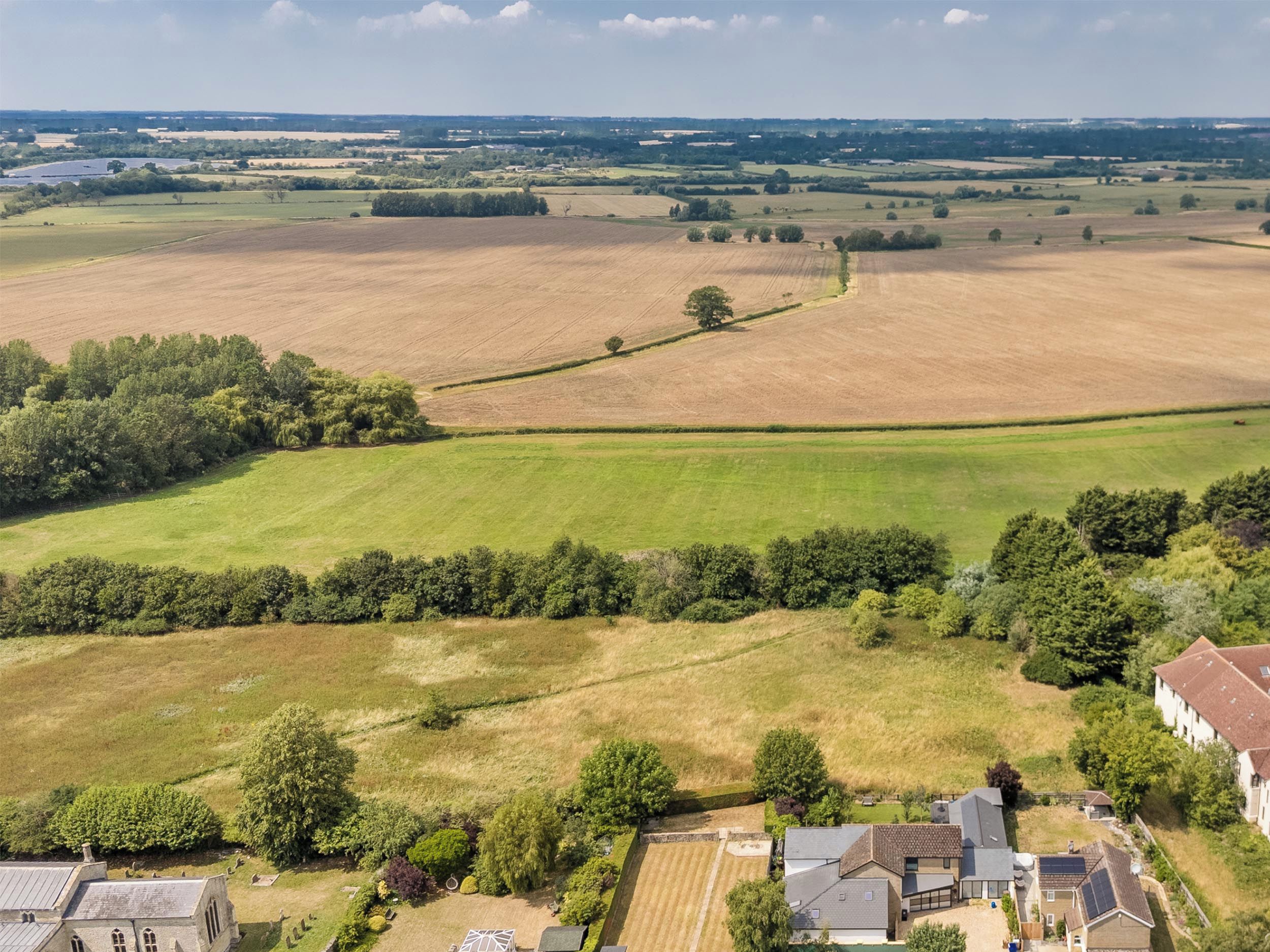 Un paisaje rural con campos, una iglesia y edificios residenciales.