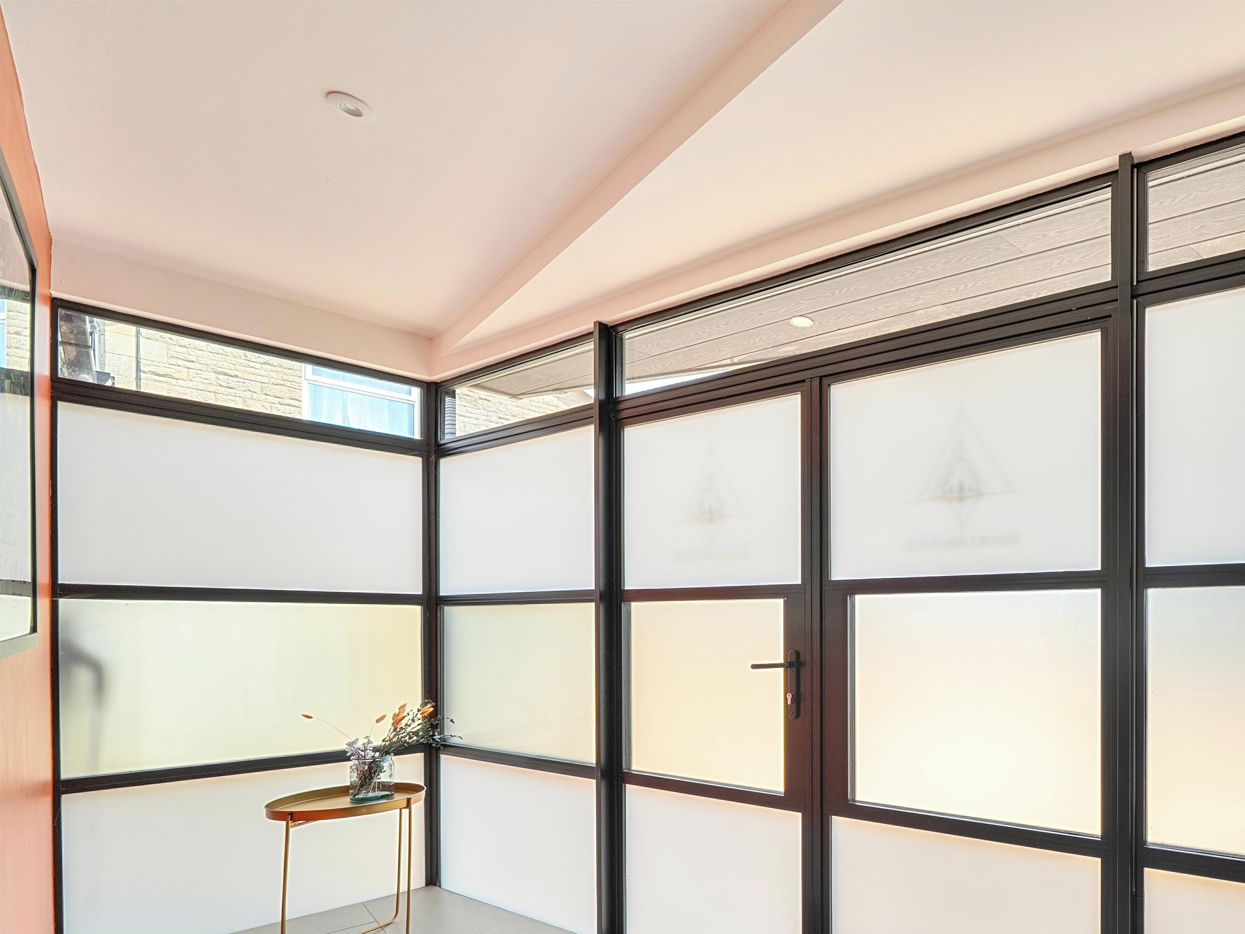 Quarto com porta deslizante, uma mesinha com um vaso e vista pela porta.