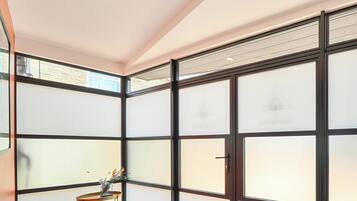Quarto com porta deslizante, uma mesinha com um vaso e vista pela porta.
