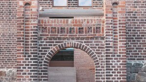 A brick building with a central arched doorway and two windows above it. - HOCHPARTERRE WEST: wood-burning stove, west-facing balcony and kitchen island (Werben)