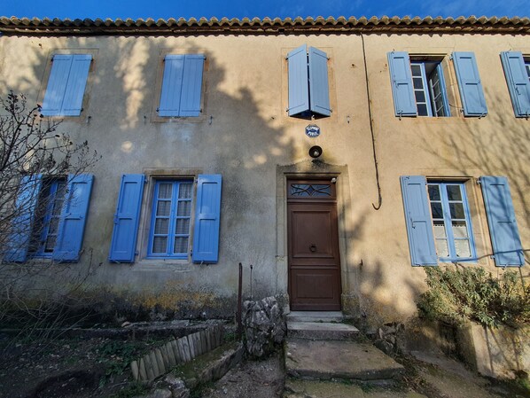 Un edificio con varias ventanas, una puerta marrón y una pequeña señal encima de la puerta.