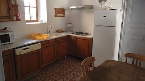 A kitchen with wooden cabinets, a sink, a stove, a microwave, and a refrigerator. - Sabatier Apartment at the Eco-Museum – Authentic 1960s Farmhouse (Gissac)