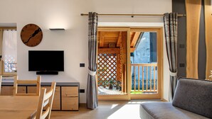 Ein modernes Wohnzimmer mit Holzboden, einem Flachbildfernseher, einem Esstisch mit Stühlen und einer Couch.