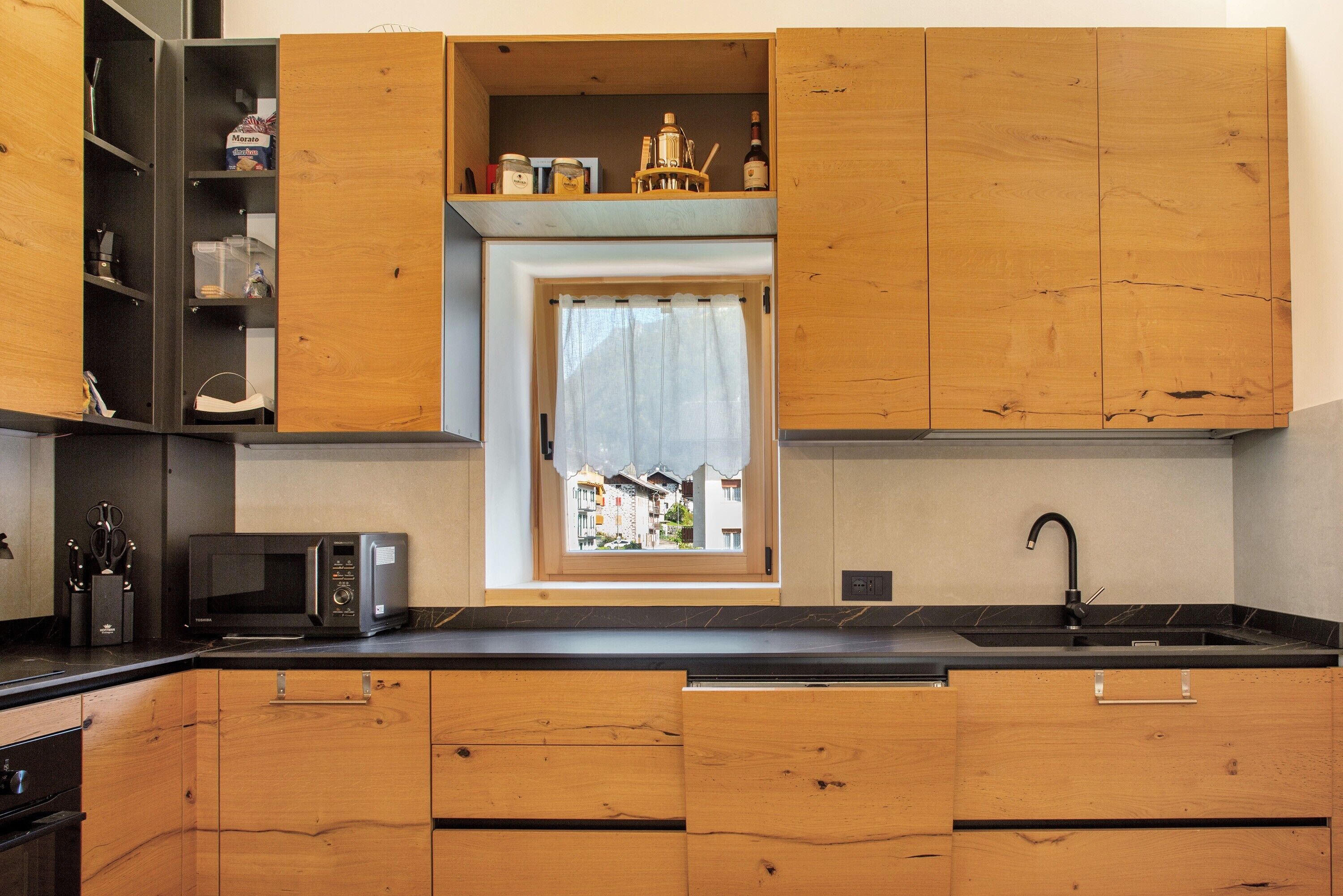 Una cucina con mobili in legno, un forno a microonde, un lavello e una finestra con vista.