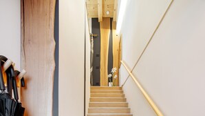 Eine Holztreppe mit Handlauf, die zu einem Zimmer mit einem Bett und einem Nachttisch führt.