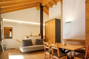 Une pièce chaleureuse avec un plafond en bois, un canapé, une table à manger avec des chaises et un buffet.