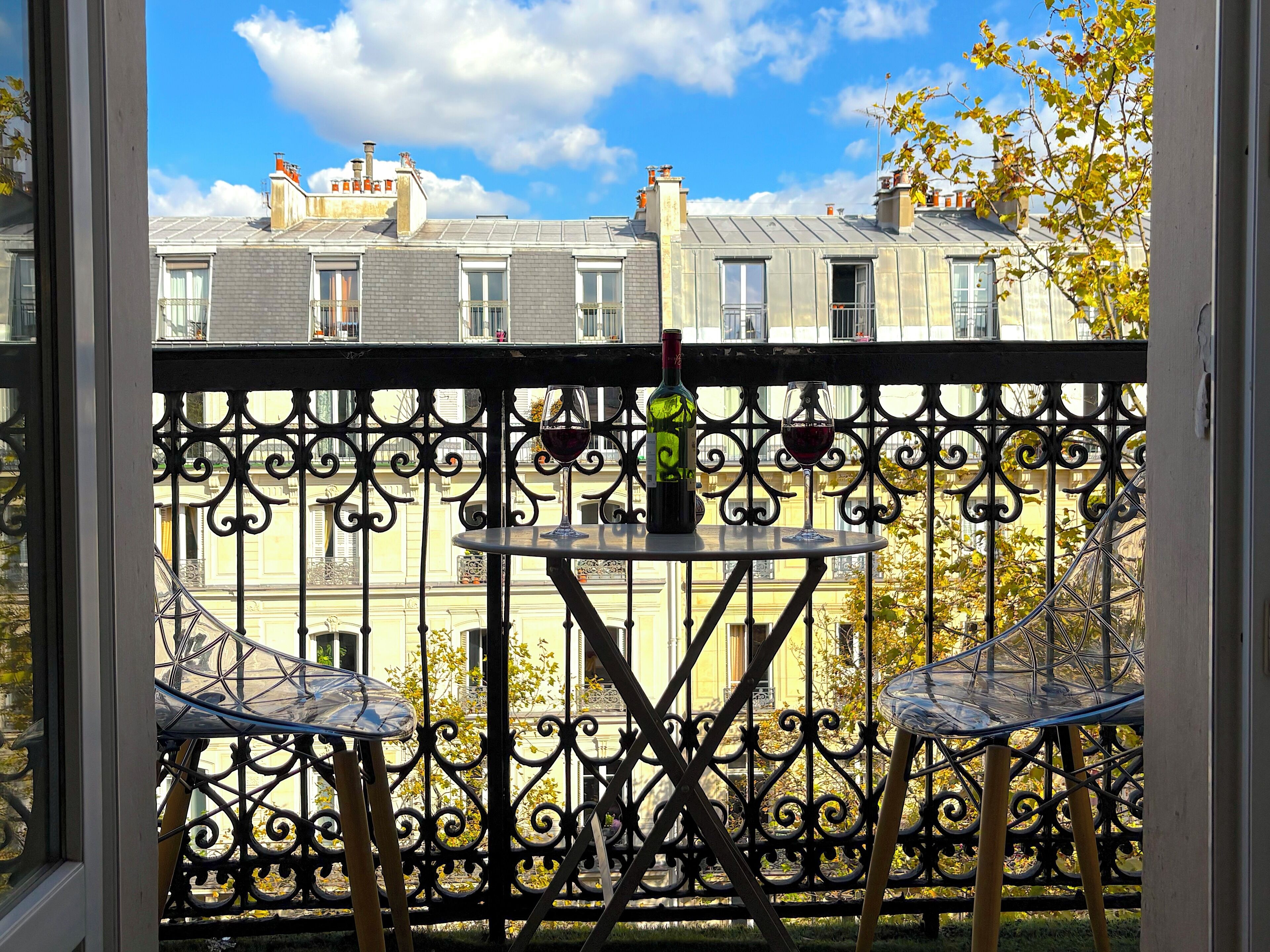 A balcony with wrought iron railings, a round table, and two chairs.
