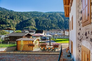 A courtyard with a wooden fence, outdoor seating, and a view of a mountain.