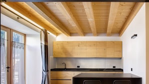 Een moderne keuken met houten kastjes, een zwart aanrecht en een eethoek met een tafel en stoelen.