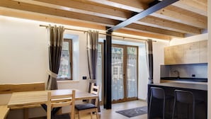 Een moderne keuken met een houten plafond, een eethoek met een tafel en stoelen, en een schuifdeur naar een buitenruimte.