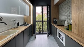 Une cuisine moderne avec des meubles gris, un plan de travail en bois et une vue sur l’extérieur.