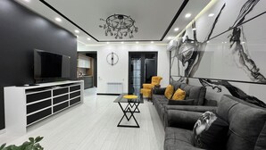 Un salon moderne avec un téléviseur à écran plat, un canapé, une table basse et un grand tableau abstrait accroché au mur.