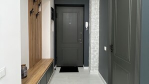 Un couloir moderne avec un banc, une porte sombre et un plancher de couleur claire.