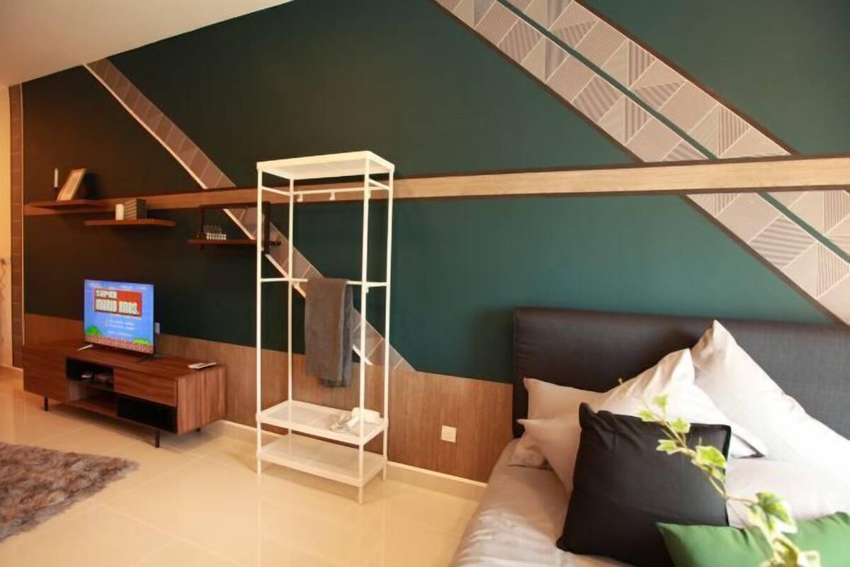 A modern living room with a sectional sofa, a white shelving unit, a television, and a patterned wall.