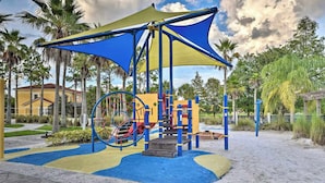 A playground with a climbing structure, a slide, and a shaded area with a canopy.