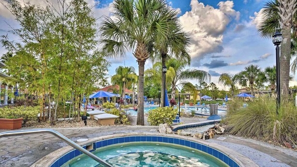 A hot tub surrounded by palm trees and a pool area with umbrellas.