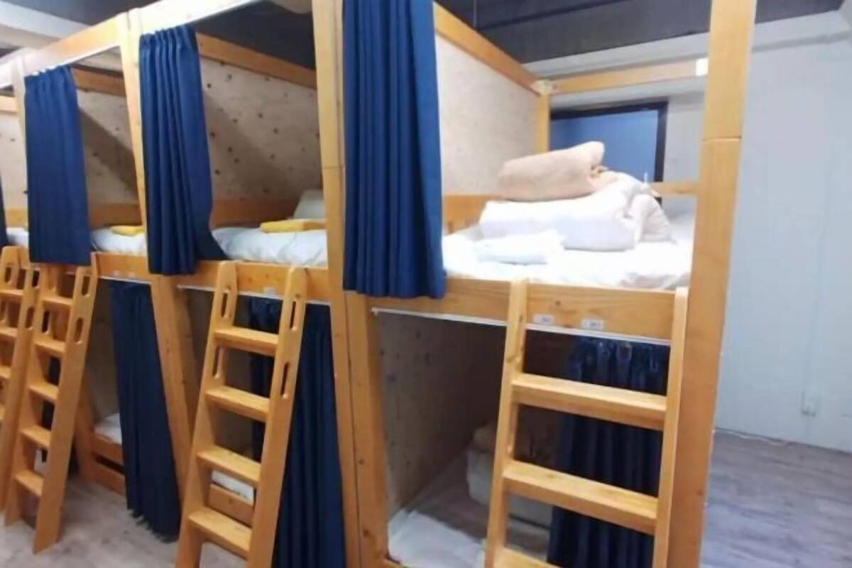 A bunk bed room with wooden frames, blue curtains, and a ladder.