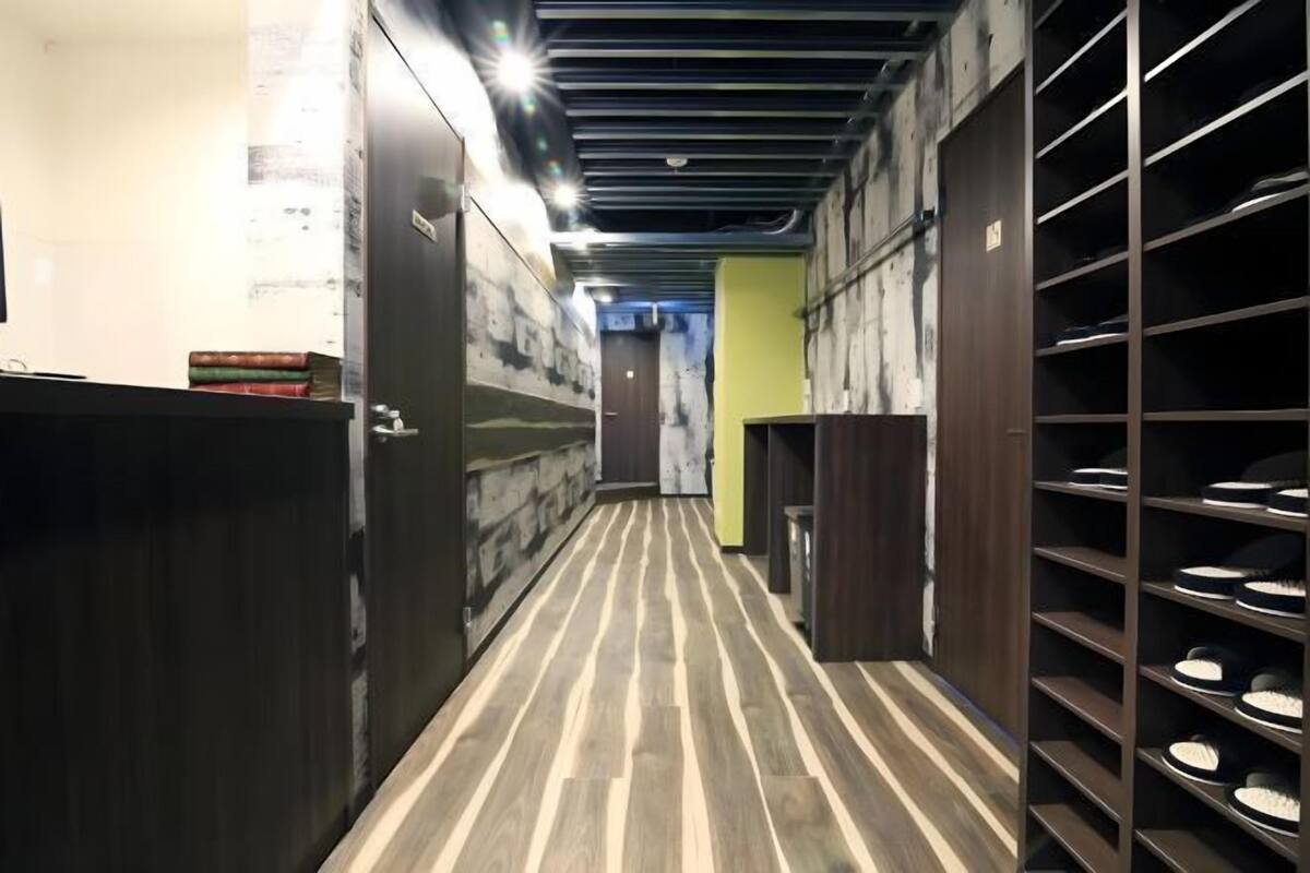 A narrow hallway with wooden flooring, metal lockers, and a door at the end.
