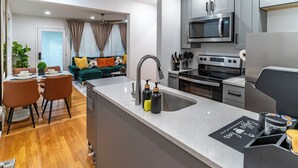 A modern kitchen with grey cabinets, a stainless steel microwave, and a built-in oven. - Limited time Deal! Cozy Luxe Escape Modern 2BR, sleeps 4,Couples, Business & Pet (Raleigh)