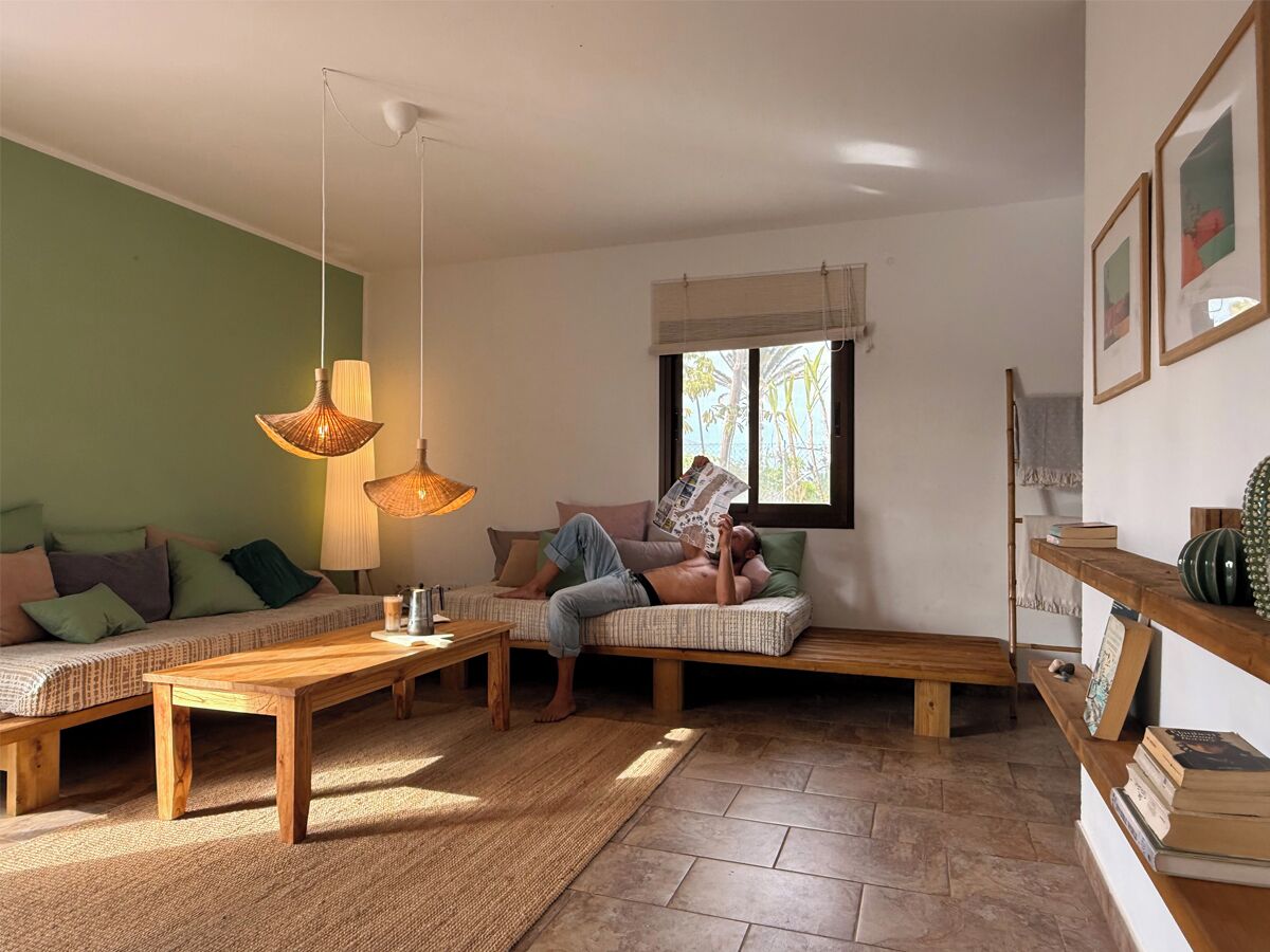 A cozy living room with a sofa, a wooden coffee table, and a reading chair.