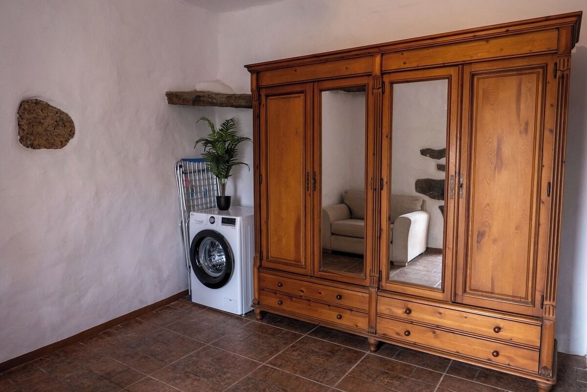 Uma área de lavanderia com máquina de lavar, um armário com gavetas e uma planta.